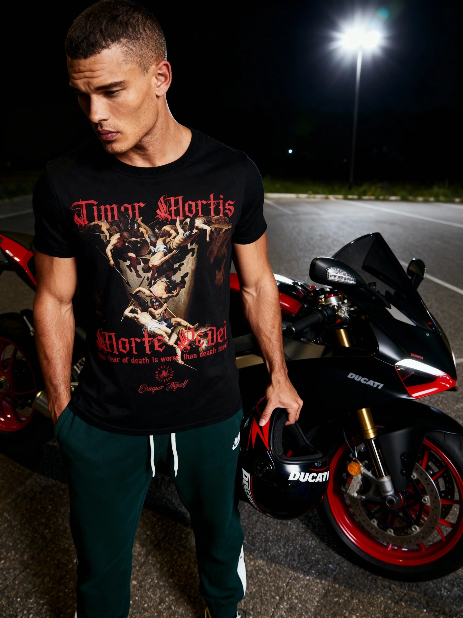 Athletic apparel men – model in Timor Mortis Latin quote gym tee beside motorcycle outdoor – Warface Athletics