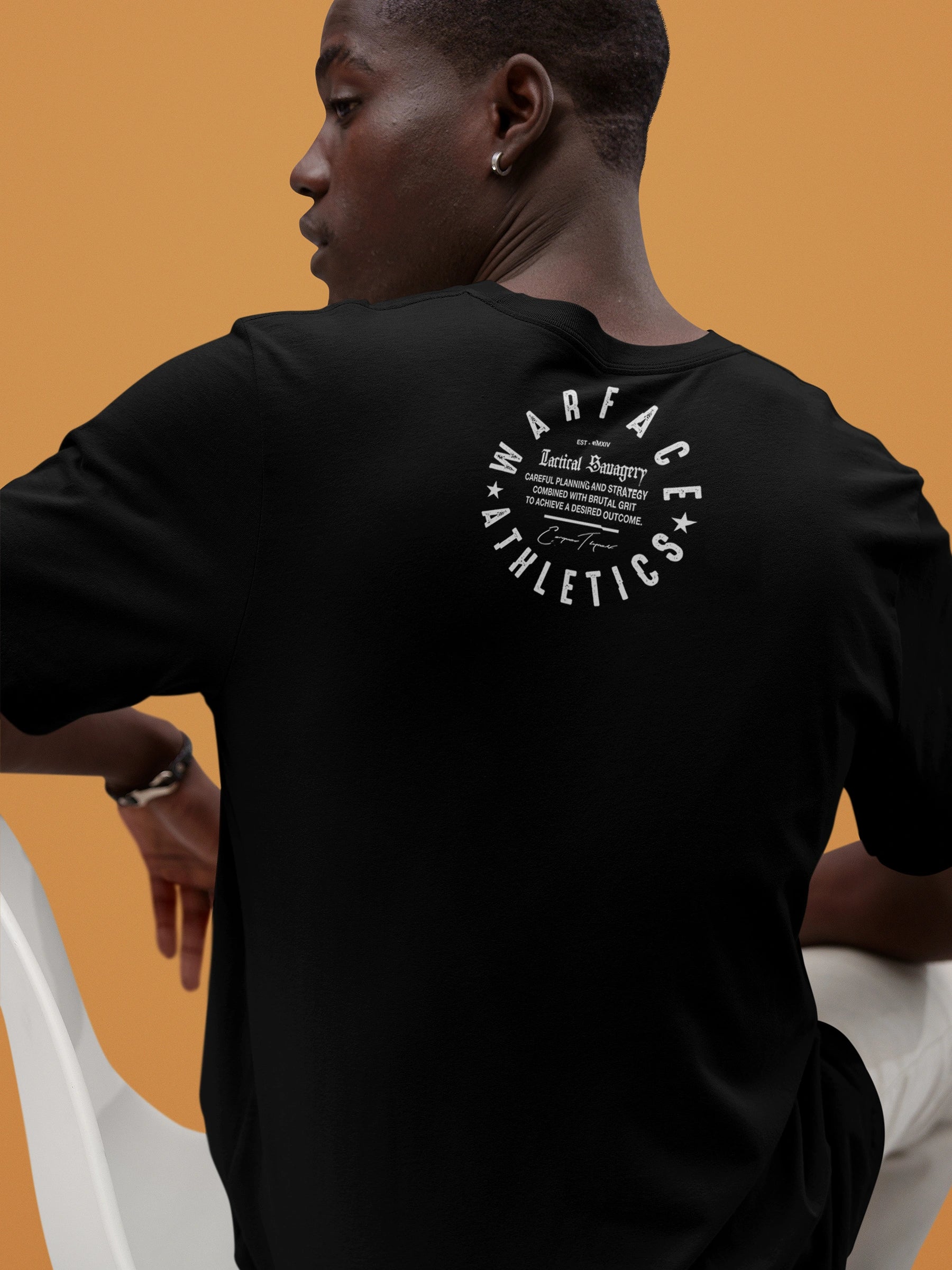 Streetwear model wearing a black gym t-shirt with 'Warface Athletics' logo on an orange background