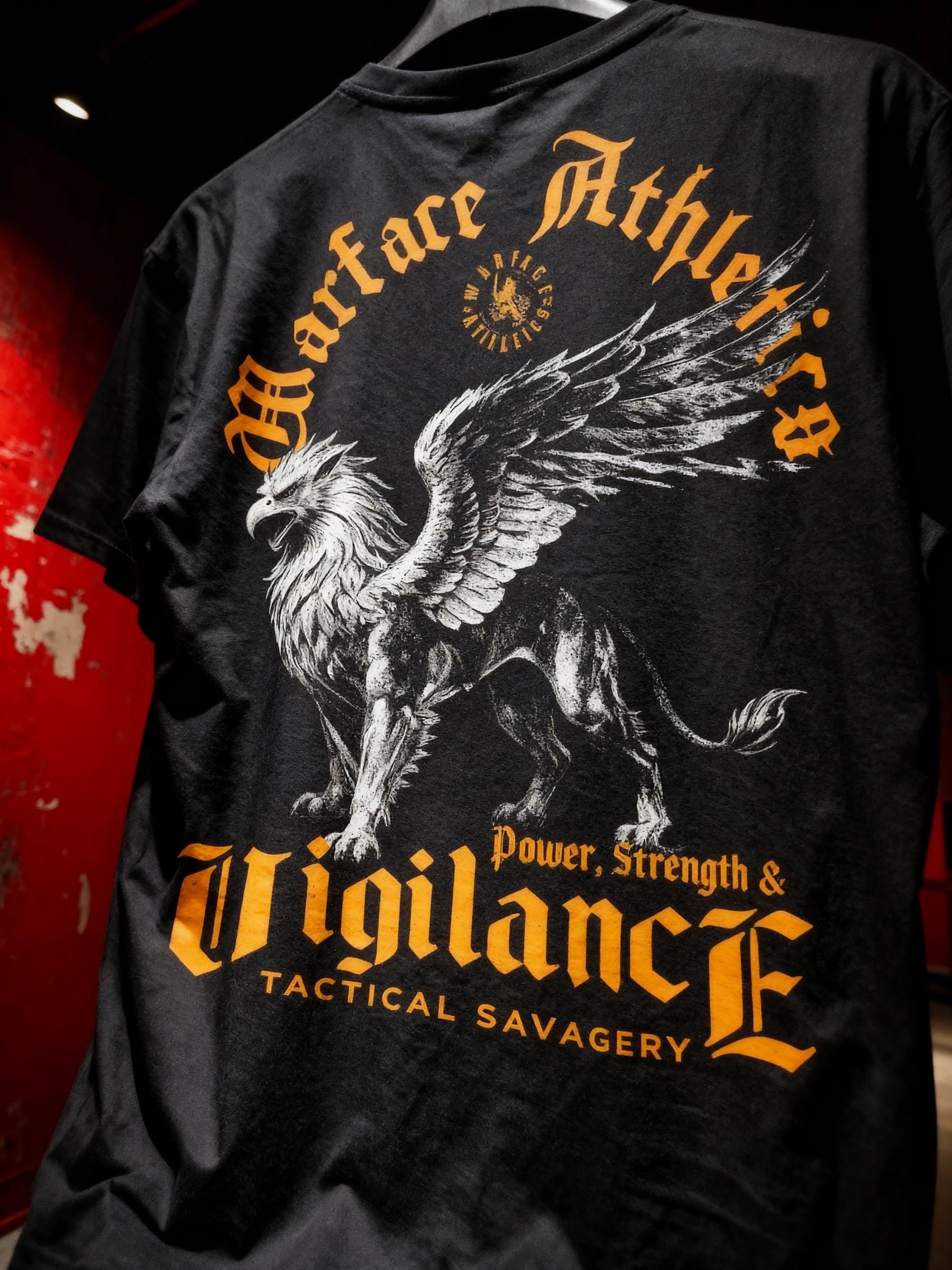 Vigilance Tee Lifestyle — Men's Stoic Warrior Shirt with Griffin Graphic and yellow Quote on red wall Setting by Warface Athletics