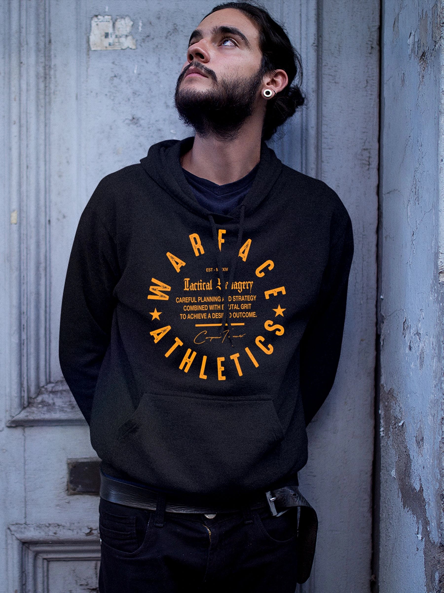 Men's Stay Unpredictable tiger gym hoodie – model in Savage Mindset black hoodie, yellow Warface Athletics text, textured wall.