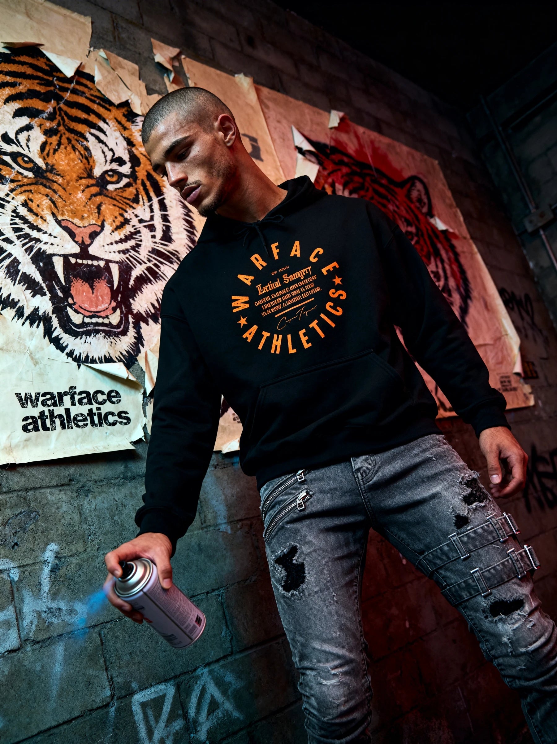 Men's Savage Mindset tiger gym hoodie – streetwear model holding spray can in front of tiger mural. Warface Athletics.