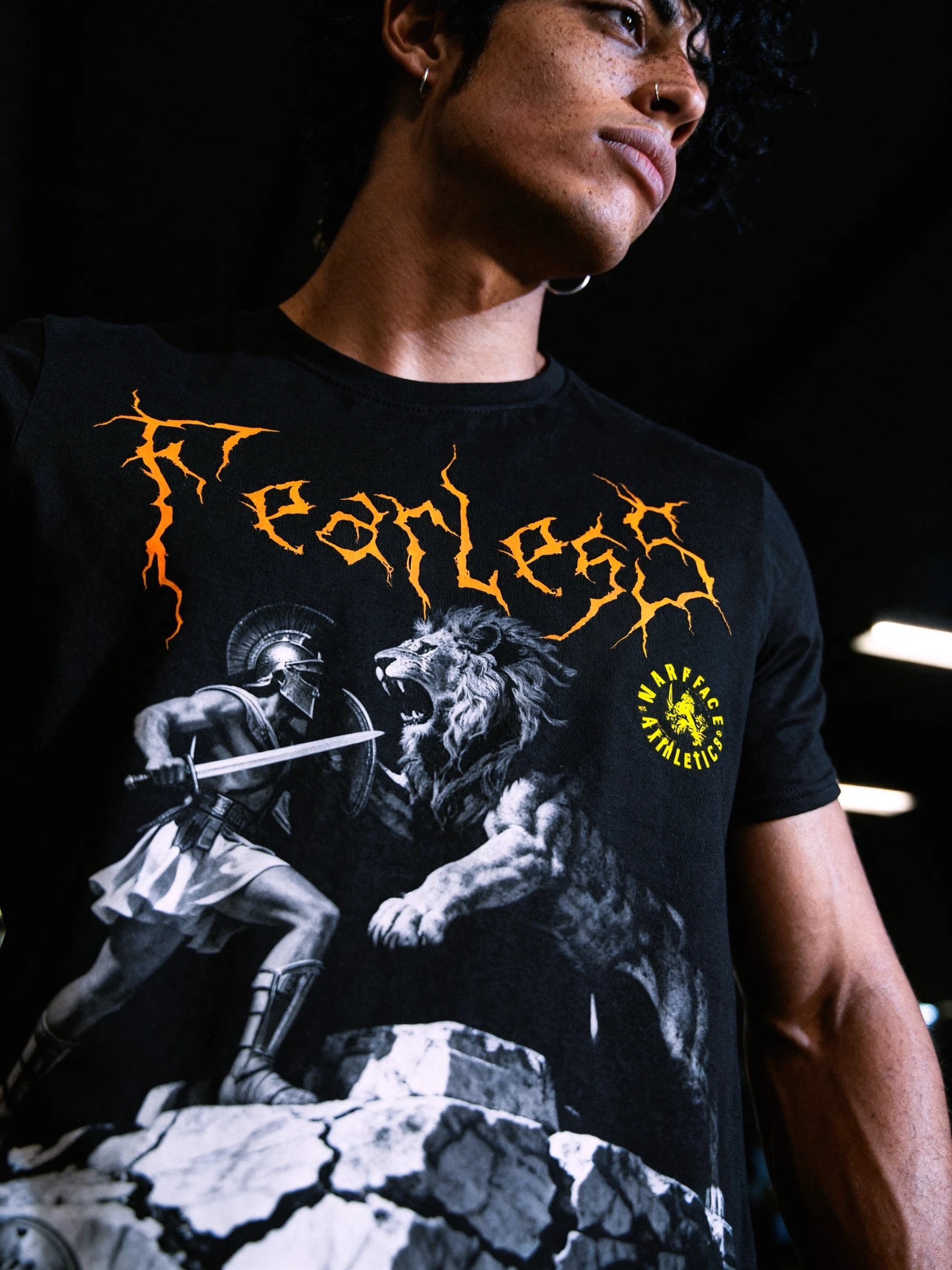 Fearless graphic tee design – Spartan warrior facing roaring lion, yellow jagged gothic text, men's gym shirt detail.