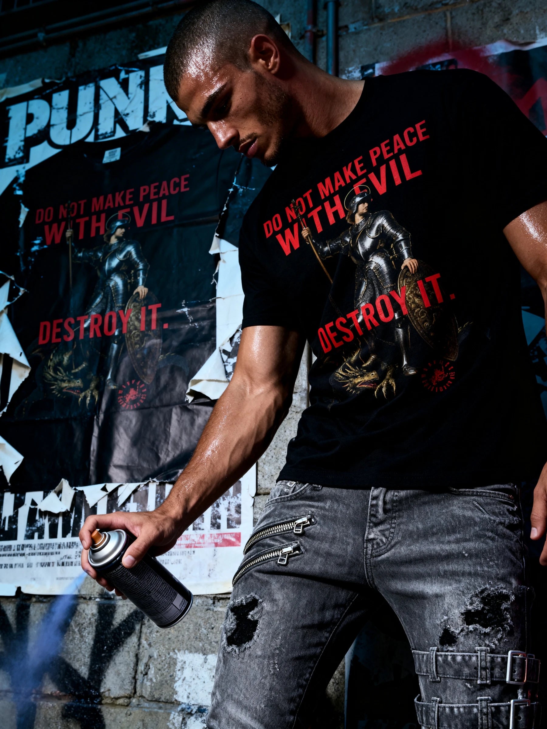 Streetwear model wearing a St George Knight t-shirt with a dragon graphic design and stoic text, standing against a graffiti-covered wall.