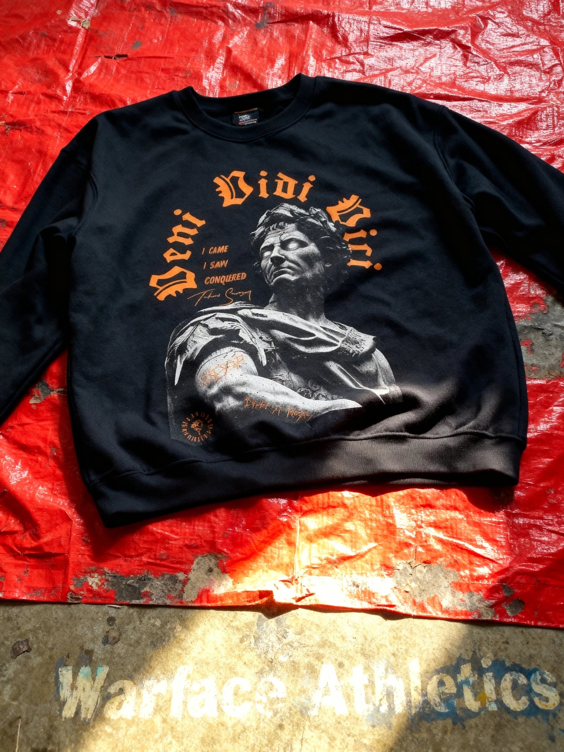 Veni Vidi Vici pump cover sweatshirt flat lay on red tarp – men's Julius Caesar roman emperor crewneck. Warface Athletics.